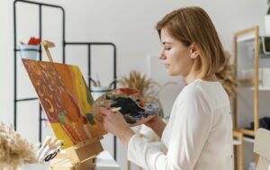 Mujer rubia pintando cuadro con óleos